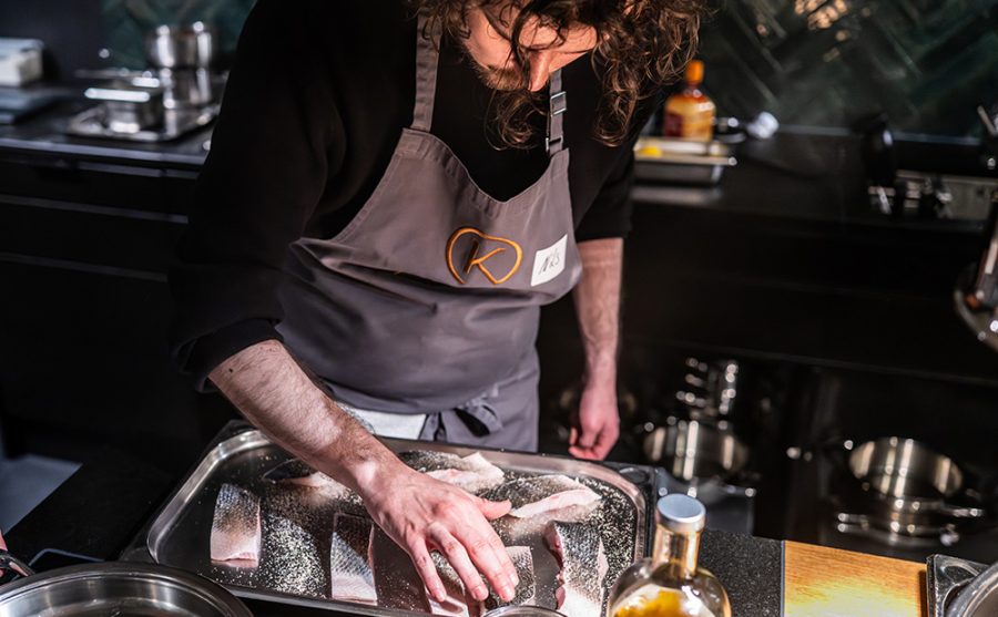 Ein Mann in der Küche, der Fischstücke bearbeitet